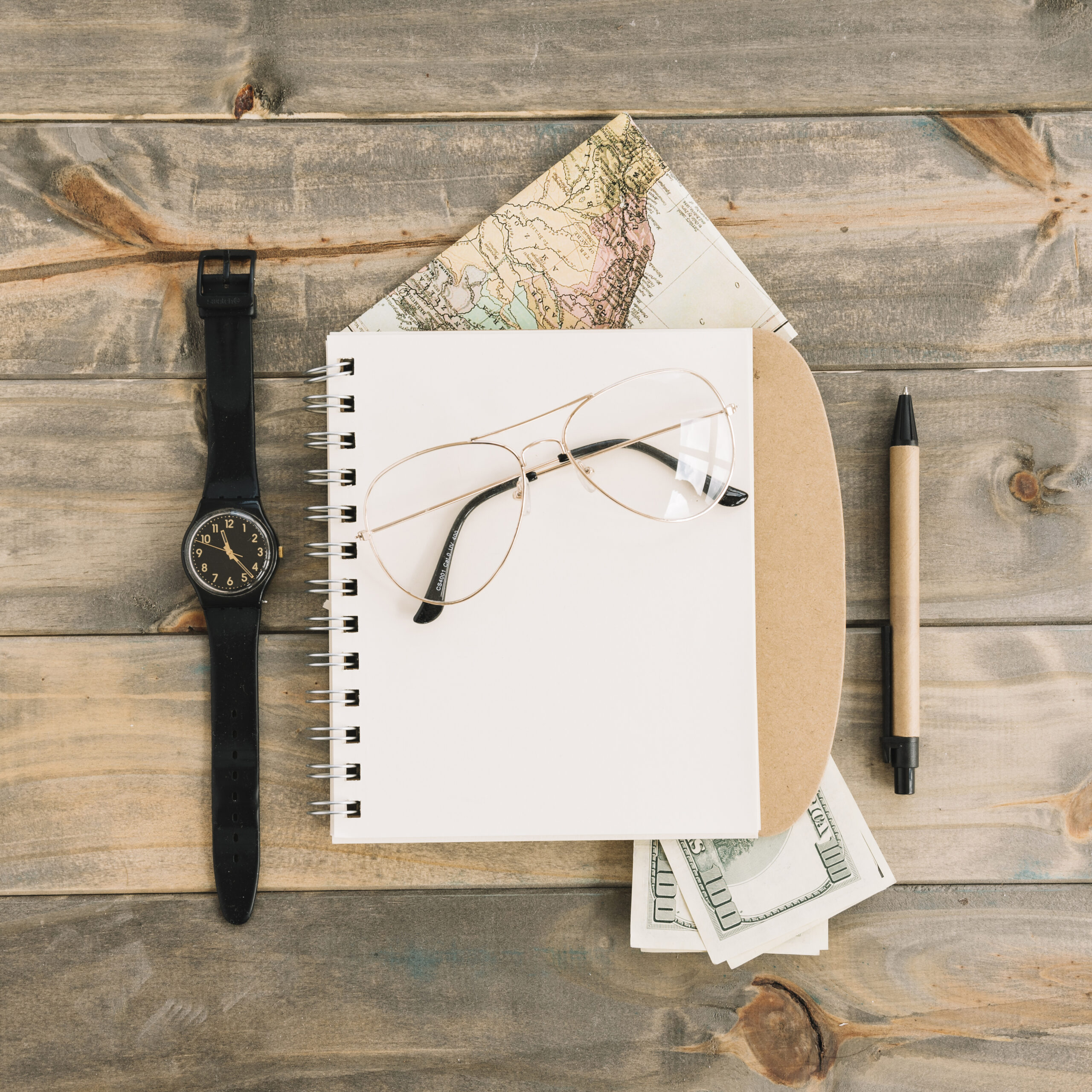 overhead-view-eyeglasses-spiral-notepad-currency-map-wristwatch-pen-wooden-plank-background Reassuring Clients While You’re Away